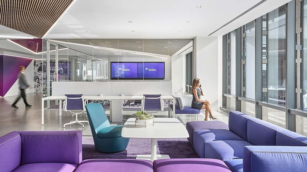 Leidos: A lounge with purple sofas and a screen beside tall windows