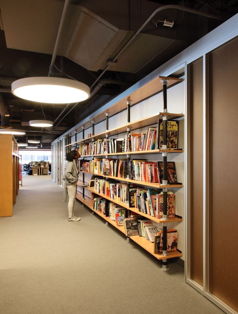 Levi Strauss & Co.: Long corridor lined with wooden bookshelves under round ceiling lights