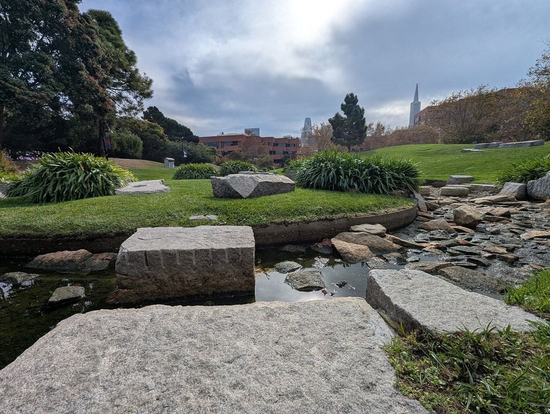 Levi Strauss & Co.: Stepping stones and granite blocks across a stream in a grassy park