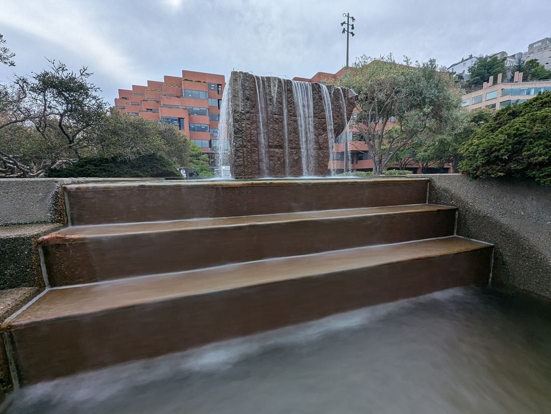 Levi Strauss & Co.: Water flowing down wide stone steps with a waterfall and brick building behind