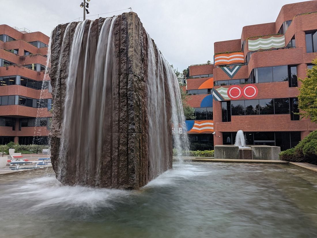 Levi Strauss & Co.: Water pouring over a large granite block into a pool in front of brick buildings