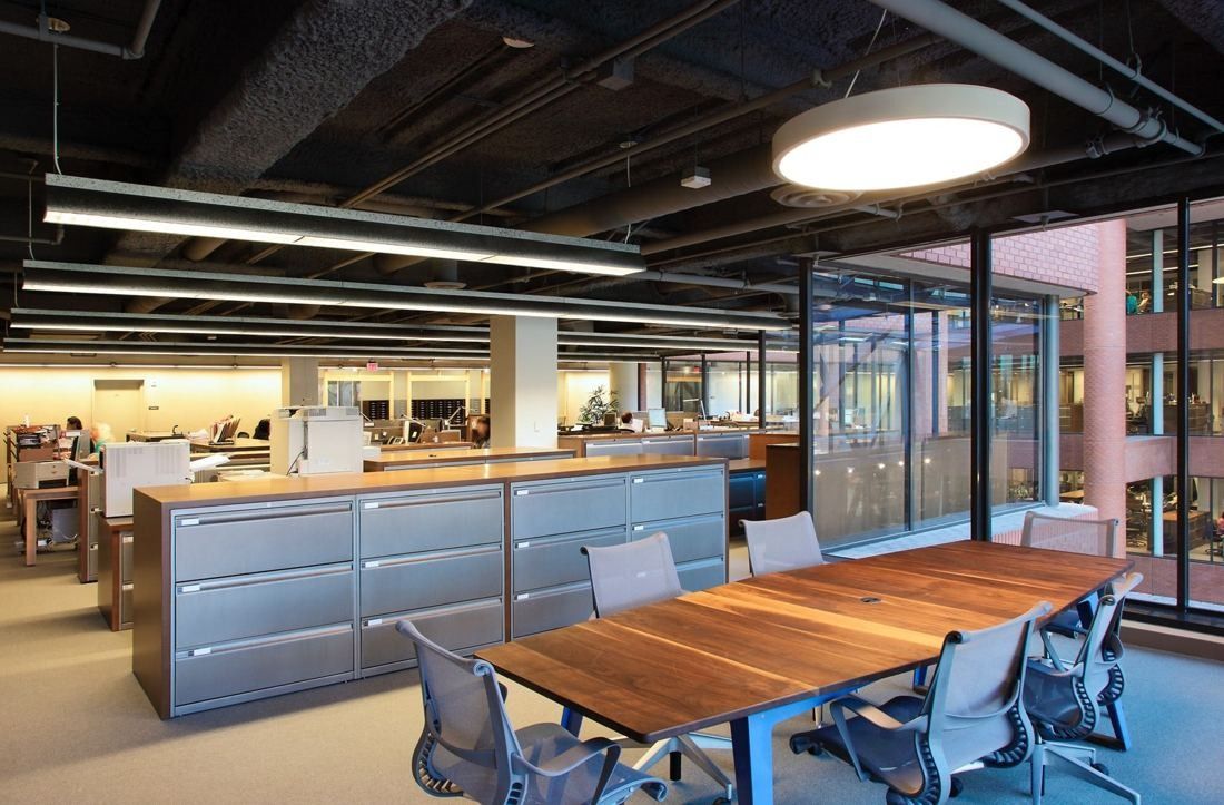 Levi Strauss & Co.: Wood meeting table with mesh chairs beside low filing cabinets on an open office floor