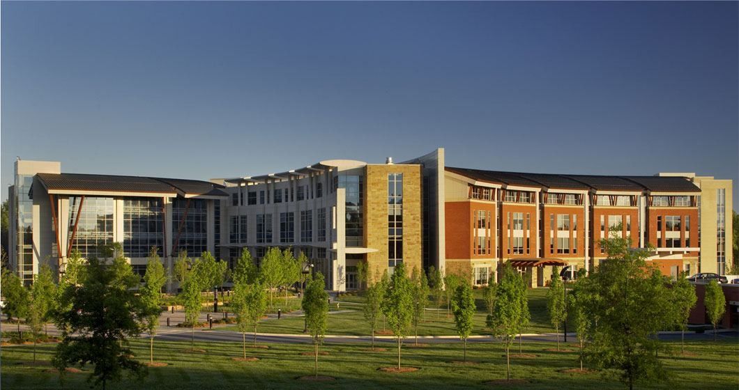 Lowe's: Brick and stone office buildings seen across a lawn with young trees in evening light