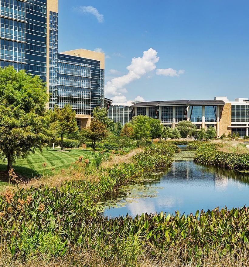 Lowe's: Planted stream channel leading toward glass office buildings under a blue sky