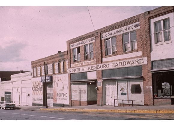 Two-storey brick store building with a 'North Wilkesboro Hardware' sign on a street corner
