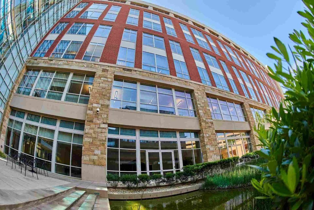 Lowe's: Wide-angle view of a brick and stone office facade with large windows beside planting