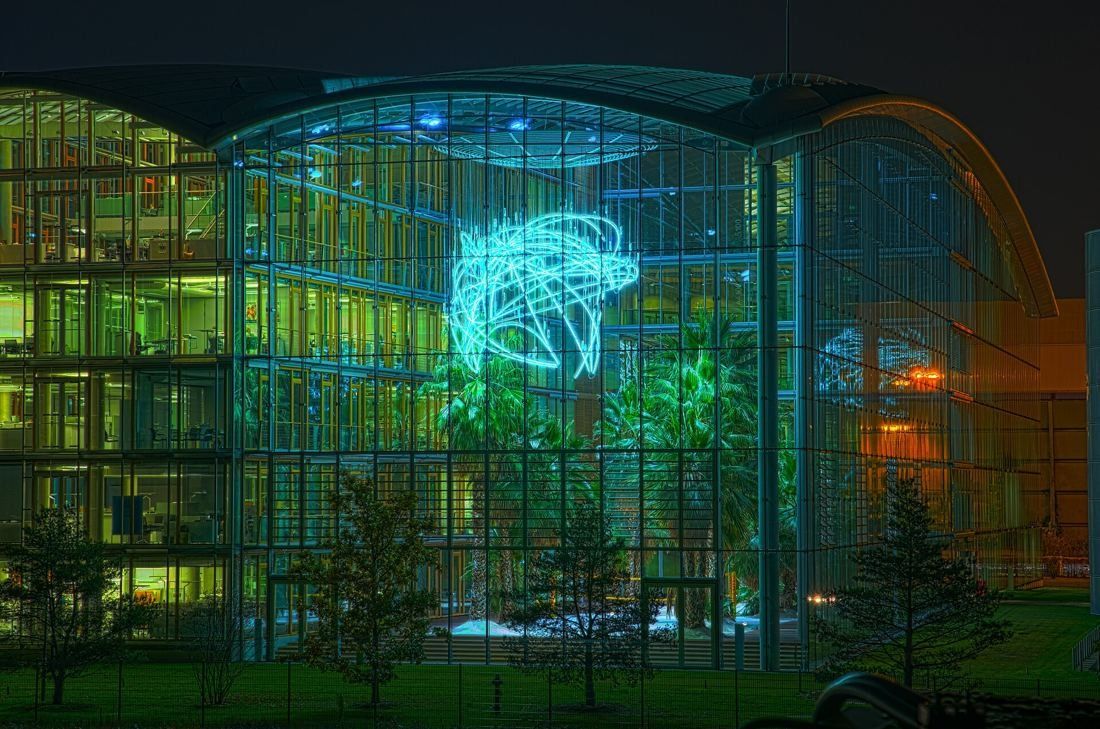 Lufthansa Group: Glass garden hall lit up at night, with a glowing light sculpture hanging above trees
