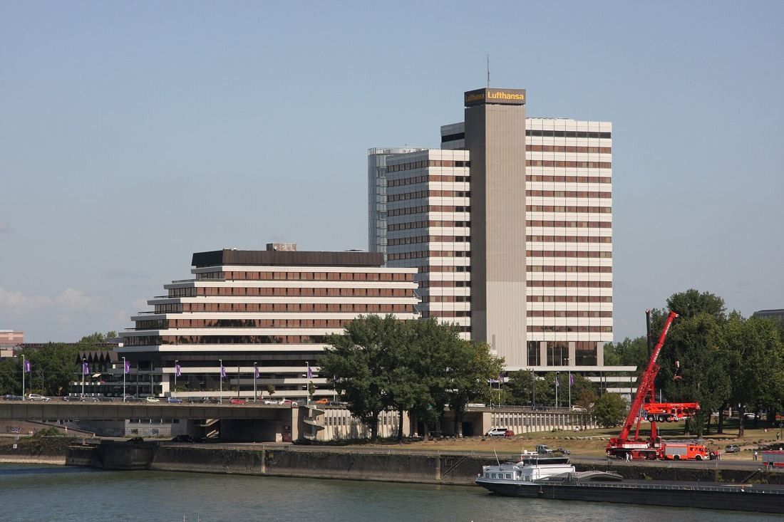 High-rise office tower with a stepped lower building on a riverbank