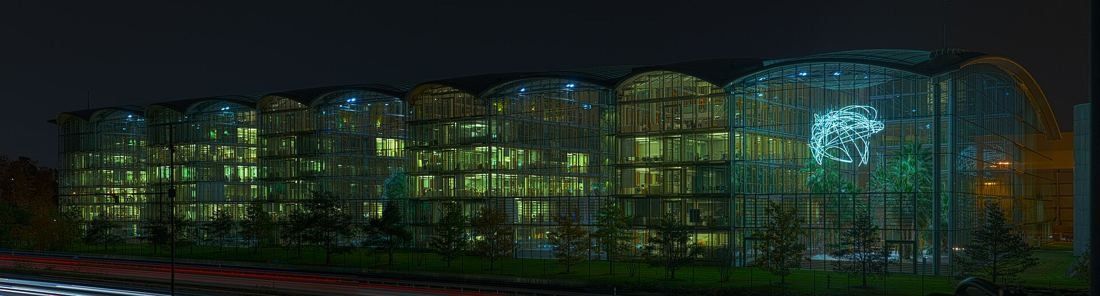 Lufthansa Group: Panorama of a long lit glass building at night