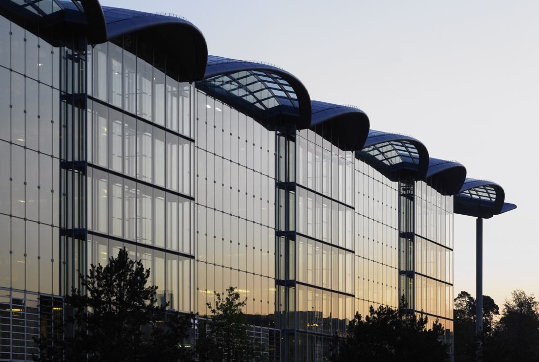 Lufthansa Group: Row of curved roof arches over a glass facade at sunset