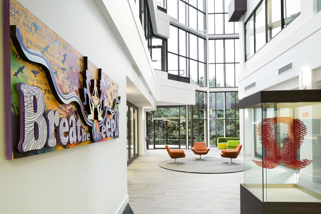 lululemon athletica: Atrium with a colourful wall sign, lounge chairs and tall windows