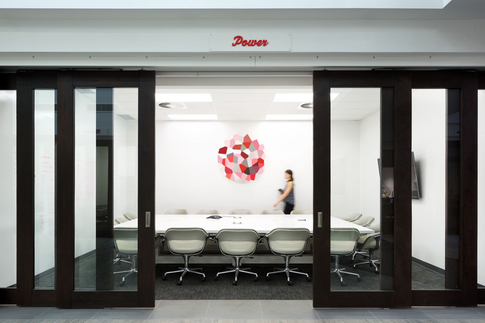 lululemon athletica: Meeting room with sliding dark-wood doors and a long white table