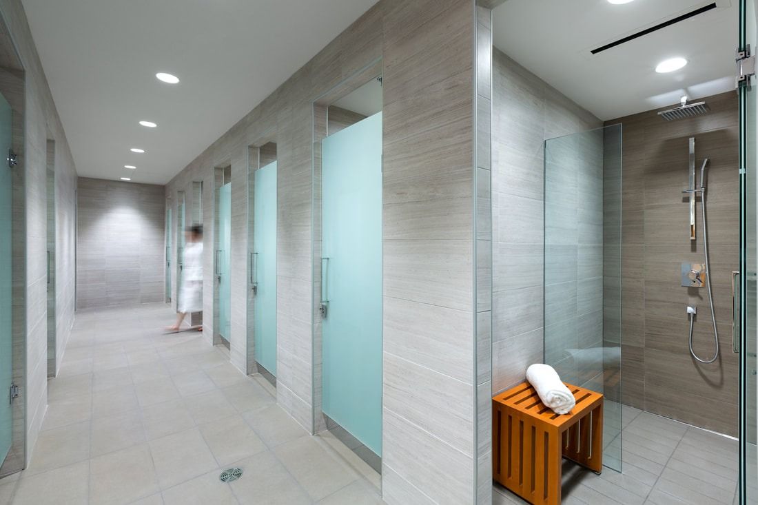 lululemon athletica: Showers with frosted glass doors and a wooden stool