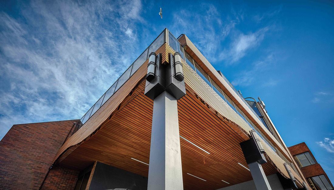 Timber canopy and steel posts on a red-brick building under a blue sky