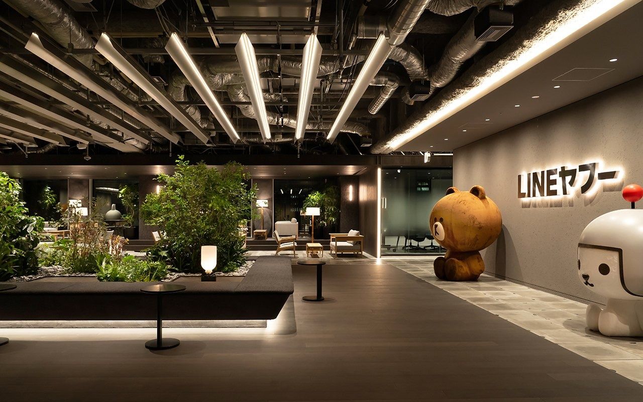 LY Corporation: Dark lounge with linear lights, plants and large character figures