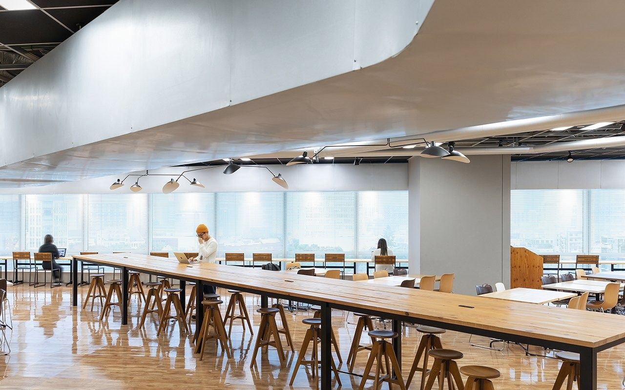 LY Corporation: Long wooden counter under a curved white ceiling by windows