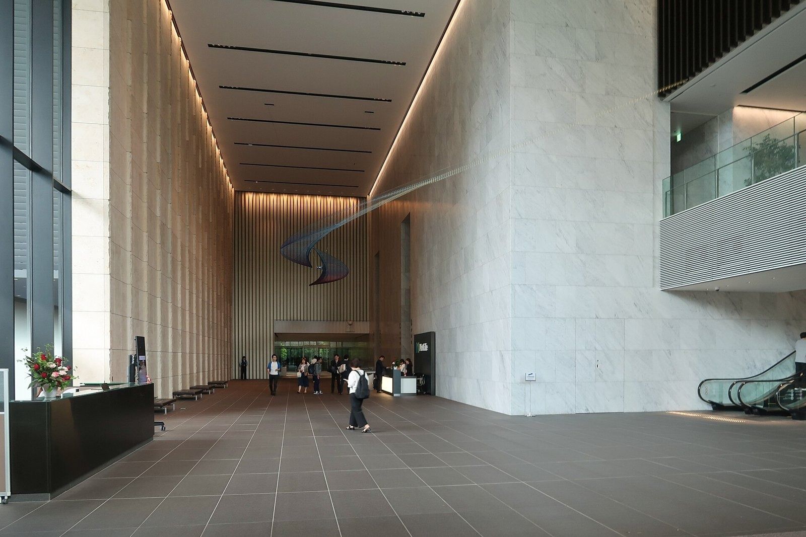 LY Corporation: Tall stone-clad lobby with escalators