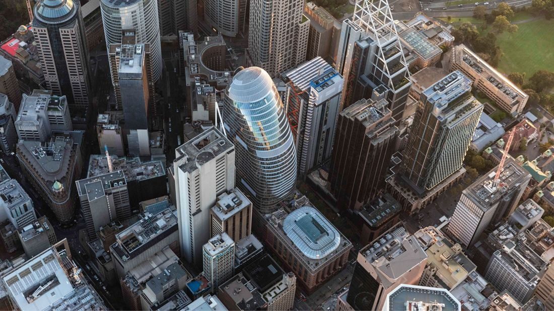 Aerial view of a curved glass tower among Sydney office blocks