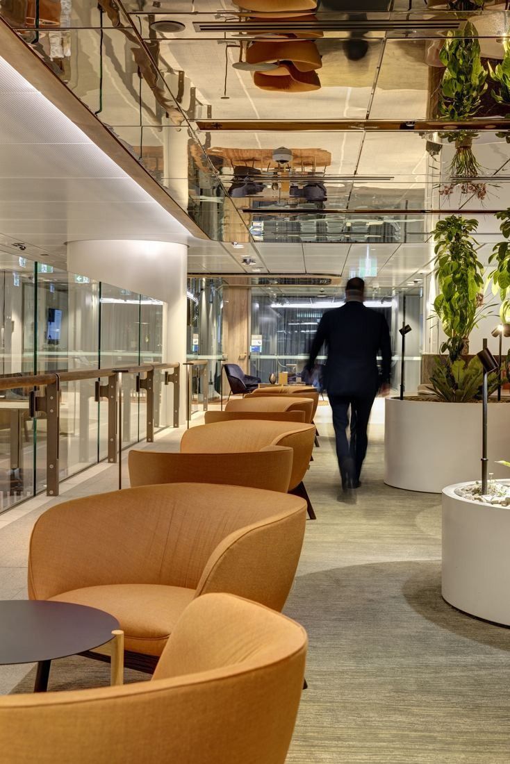 Macquarie Group: Orange lounge chairs along a corridor with hanging plants