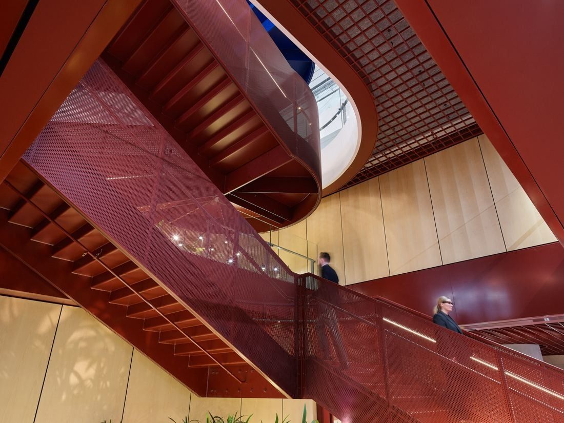 Macquarie Group: Sweeping red staircase rising through a timber-lined void