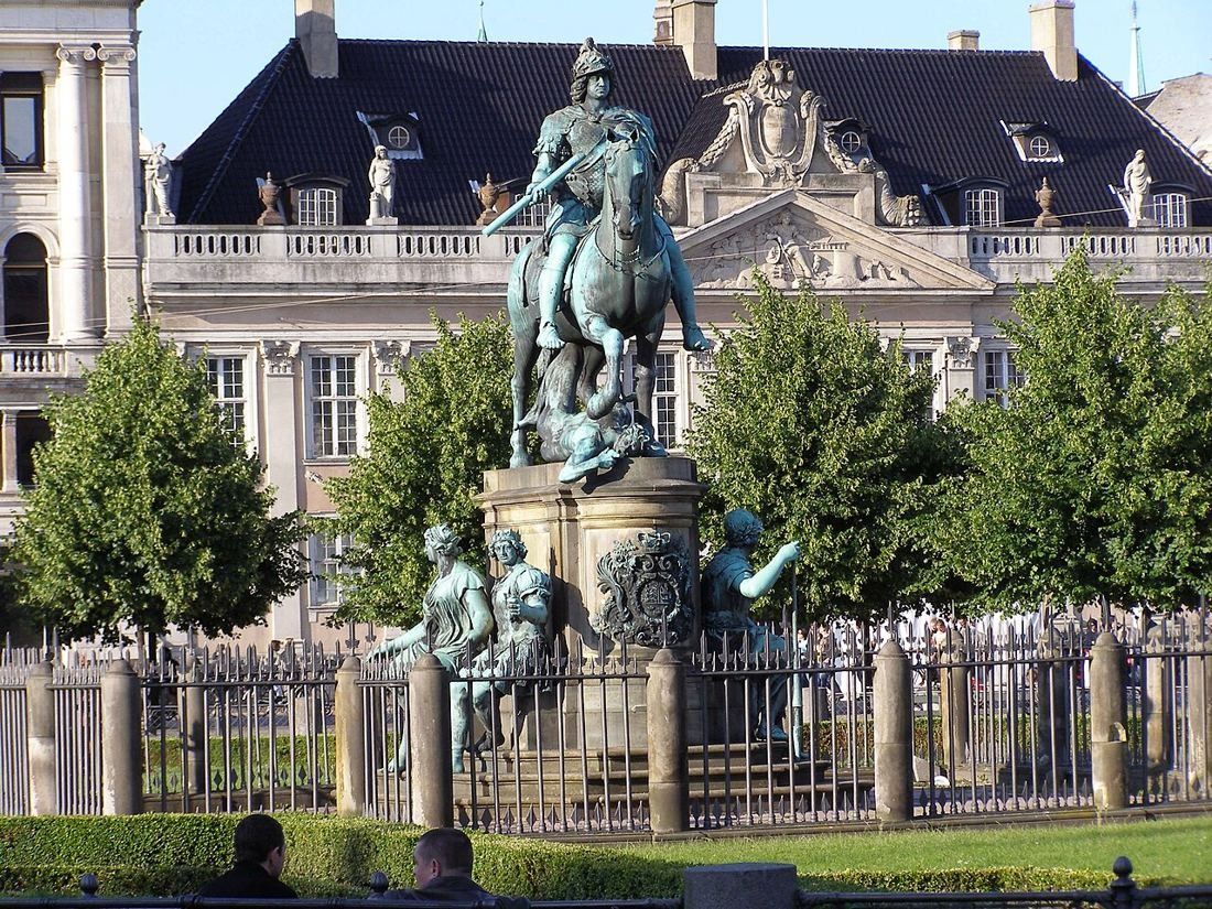 Equestrian statue in the middle of Kongens Nytorv square in front of a baroque palace