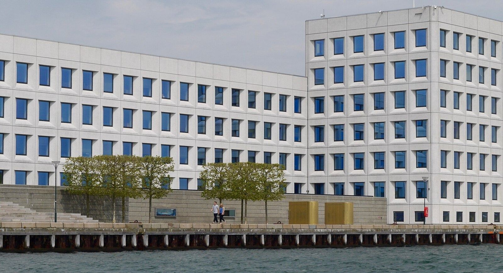 A.P. Moller - Maersk: Low and tall wings of the pale building with trees along the quay