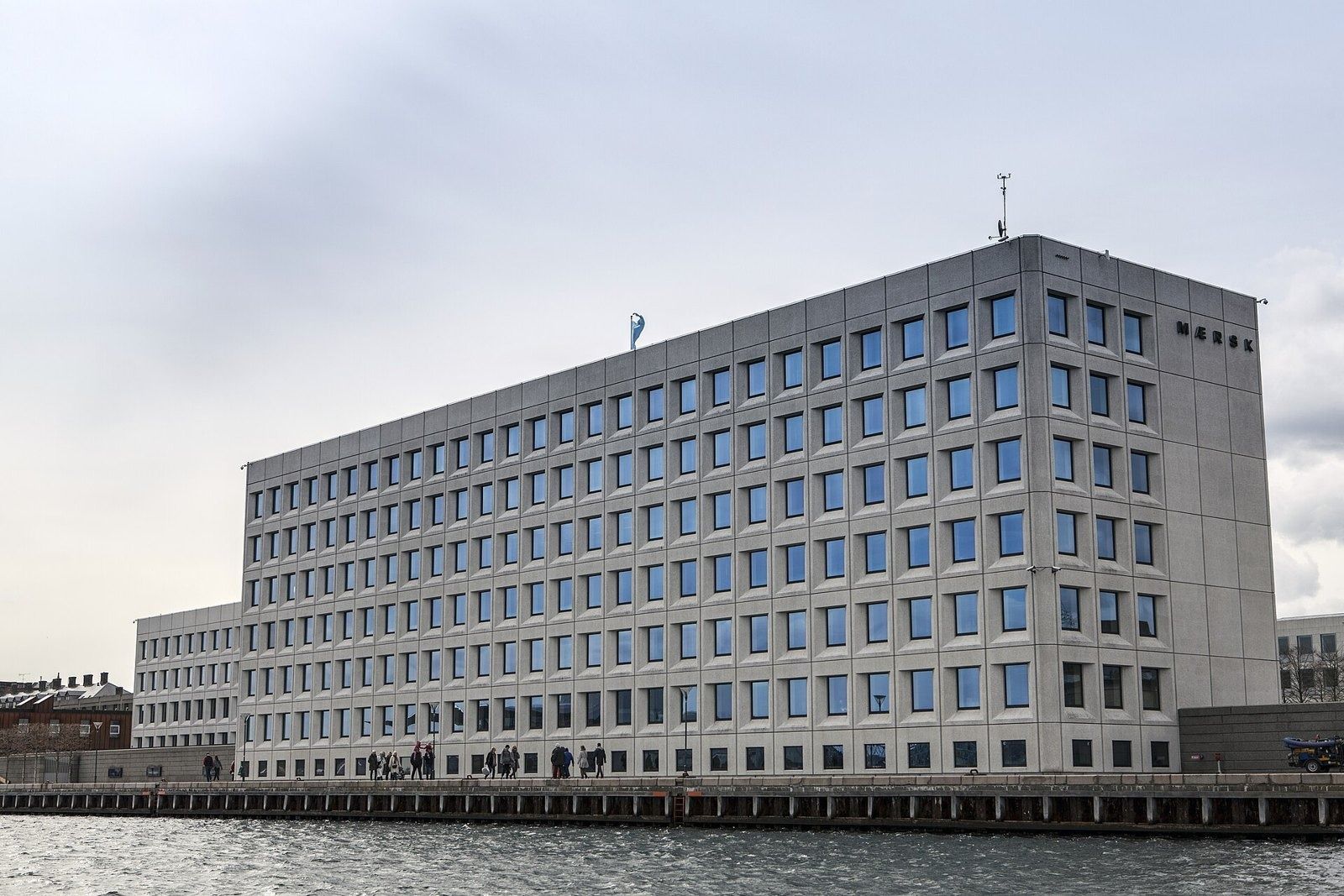 A.P. Moller - Maersk: Pale office block on the quay seen across the water under a grey sky