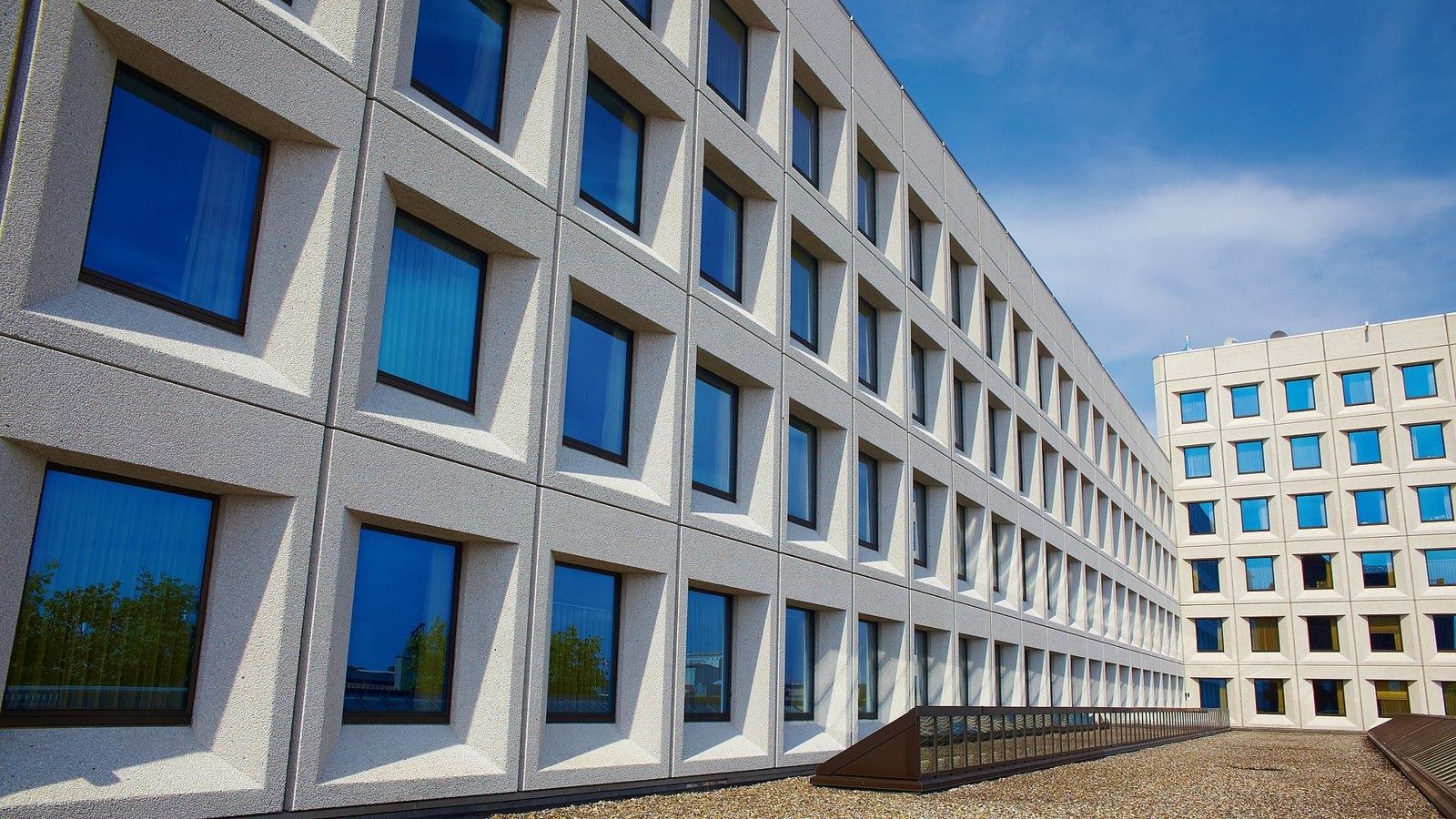 A.P. Moller - Maersk: Receding facade of deep square windows with the taller block at the end