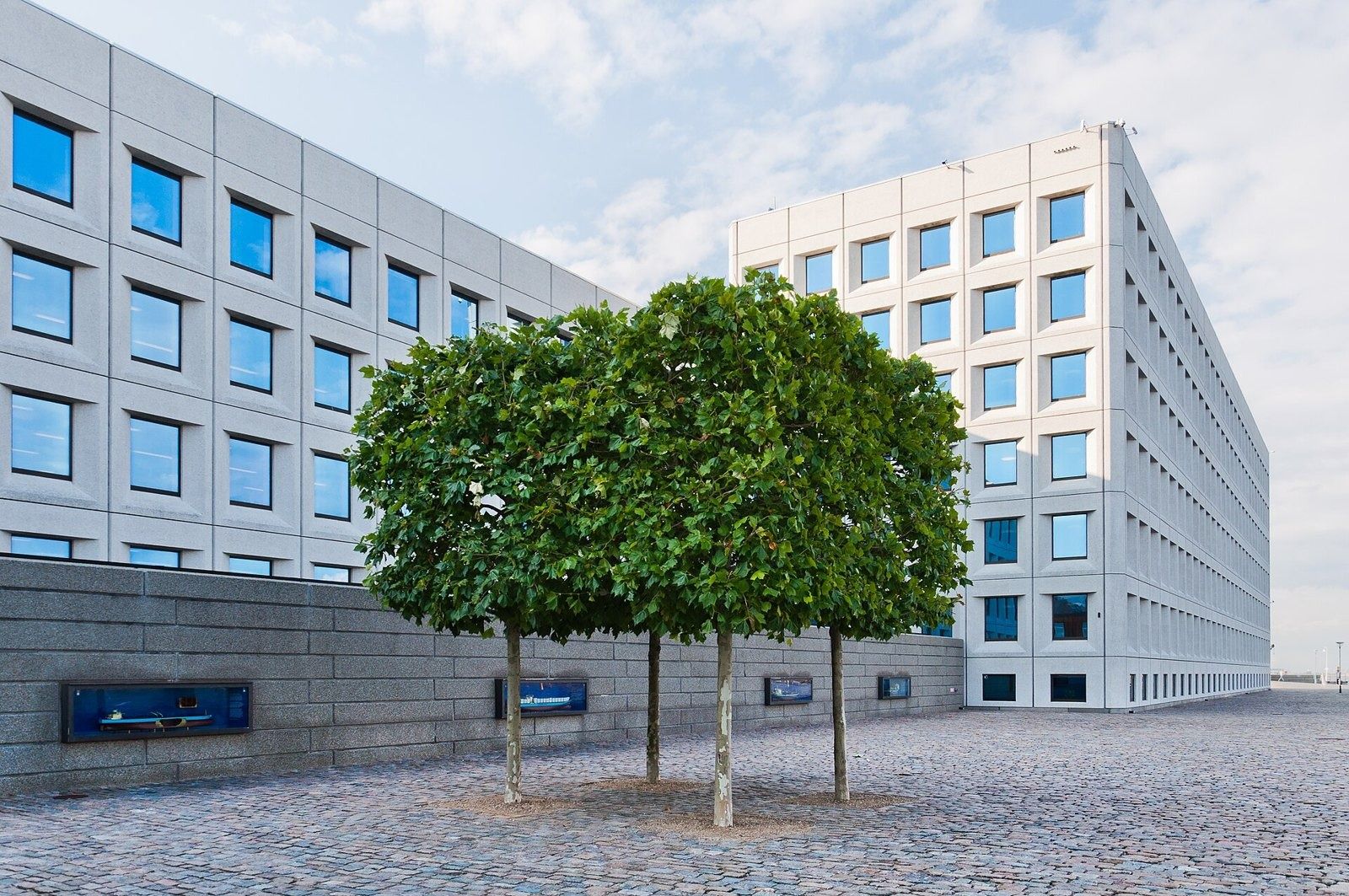 A.P. Moller - Maersk: Two wings of the building with a square of clipped trees on a gravel forecourt