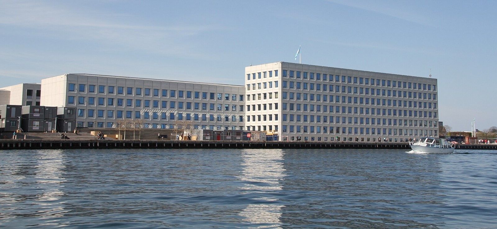 A.P. Moller - Maersk: Wide view of the low and tall blocks along the waterfront with a small boat passing