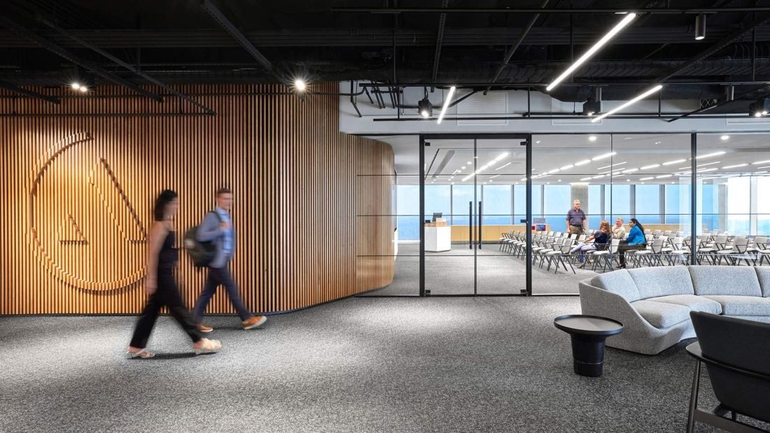 Marriott International: Corridor along a slatted wooden wall leading to a glass-walled room filled with rows of chairs