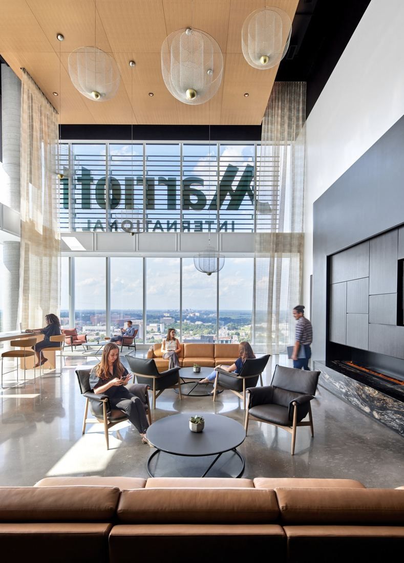 Marriott International: Double-height lounge with armchairs, a fireplace wall and a Marriott International sign on the window