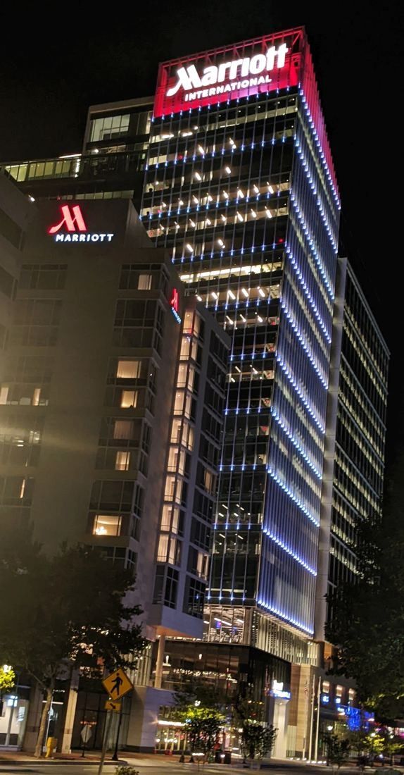 Marriott International: Glass tower at night with a lit red Marriott sign at the top