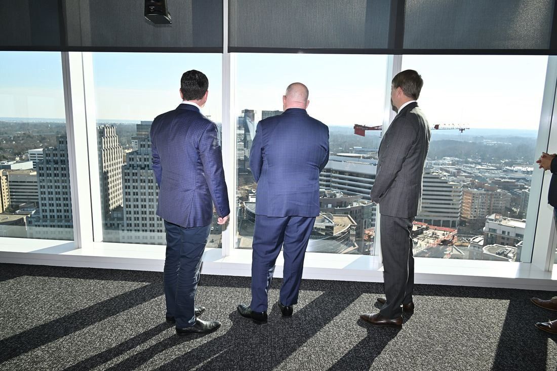 Marriott International: Three men seen from behind looking out of floor-to-ceiling windows over Bethesda