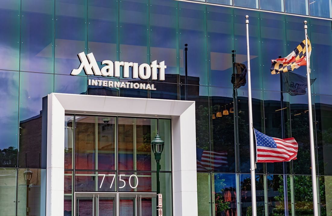 Marriott International: White entrance portal marked 7750 under a Marriott International sign, with flags reflected in the glass