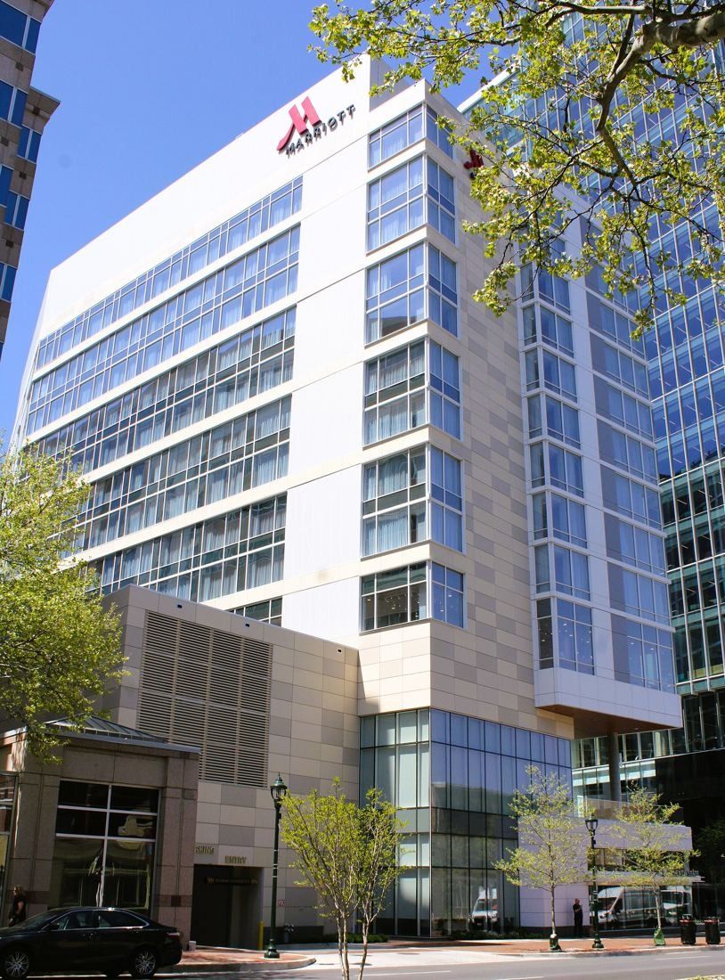 Marriott International: White hotel tower with a Marriott logo at the top, seen from below through tree branches