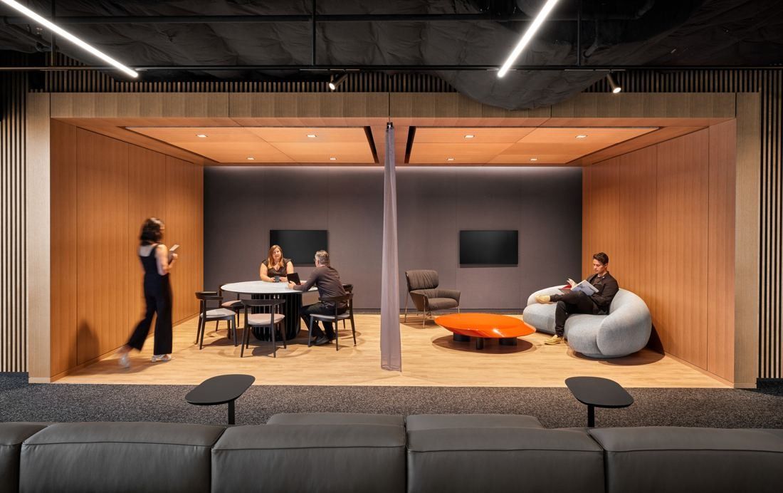 Marriott International: Wood-lined open lounge alcove with a round table, armchairs and wall screens