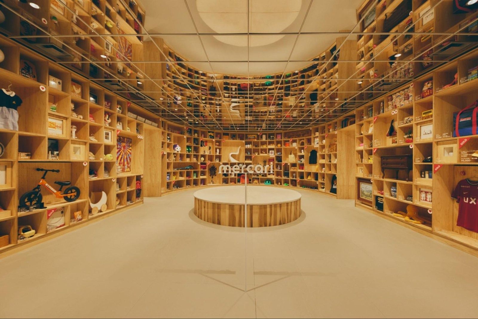 Curved walls of wooden shelves filled with objects around a round platform