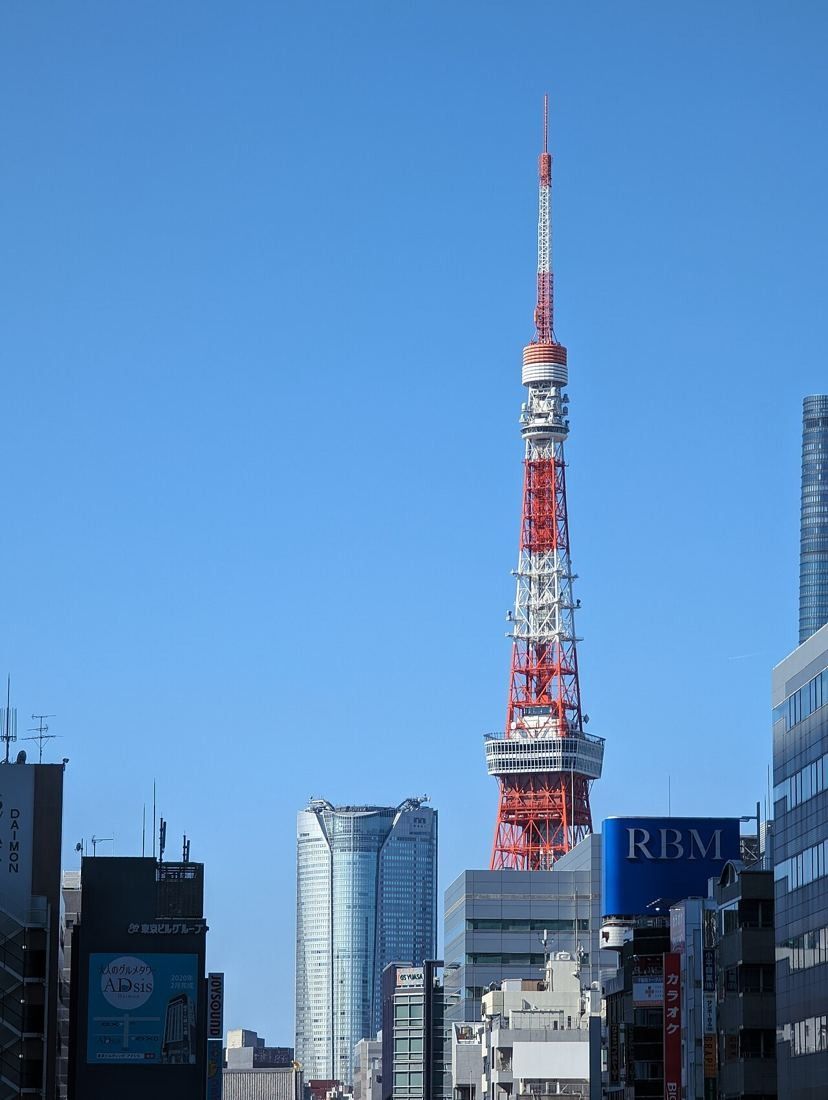 Roppongi Hills Mori Tower rising beside Tokyo Tower against a clear blue sky