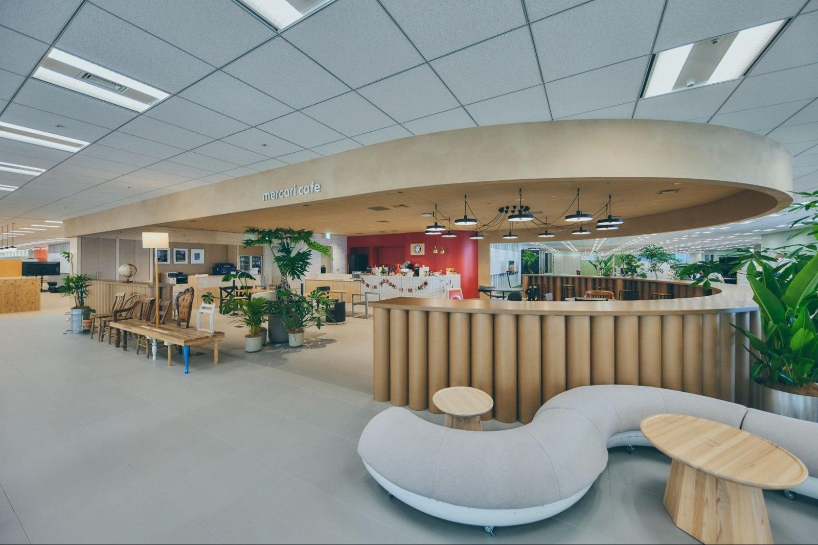 Mercari: Open floor with a curved wooden counter, white curving sofa and plants