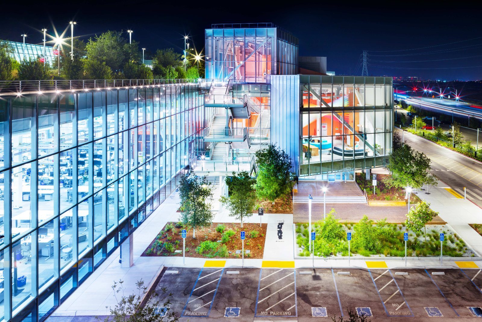 Meta: Glass building lit up at night with a rooftop garden