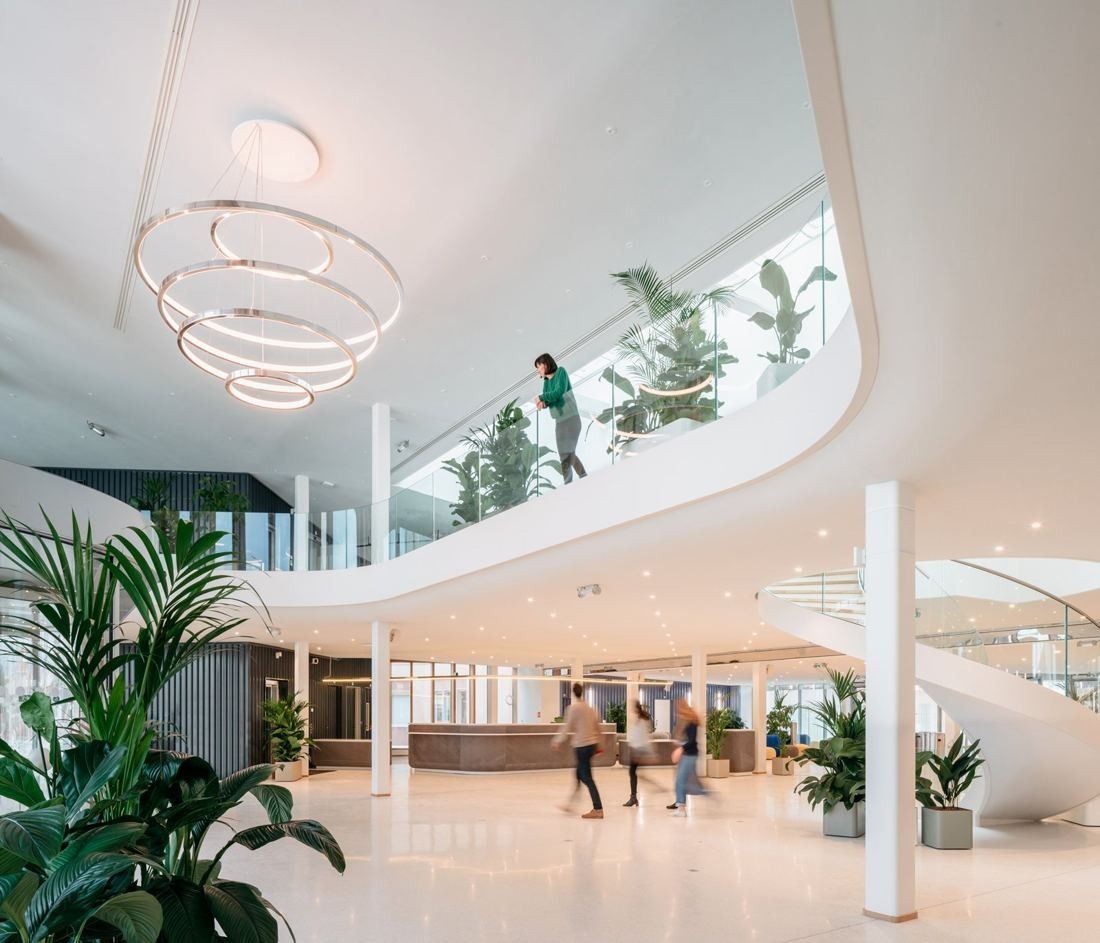 Michelin: Bright double-height hall with a ring chandelier, a curved white mezzanine and a spiral stair