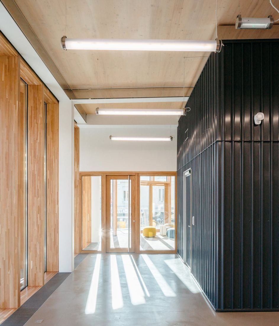 Michelin: Corridor with timber walls, a black ribbed wall panel and sunlight on the floor