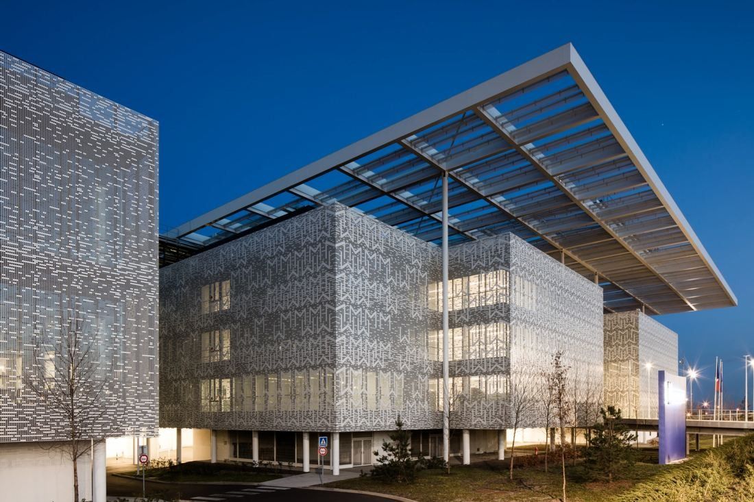 Michelin: Office block with a perforated metal skin under a projecting canopy at dusk