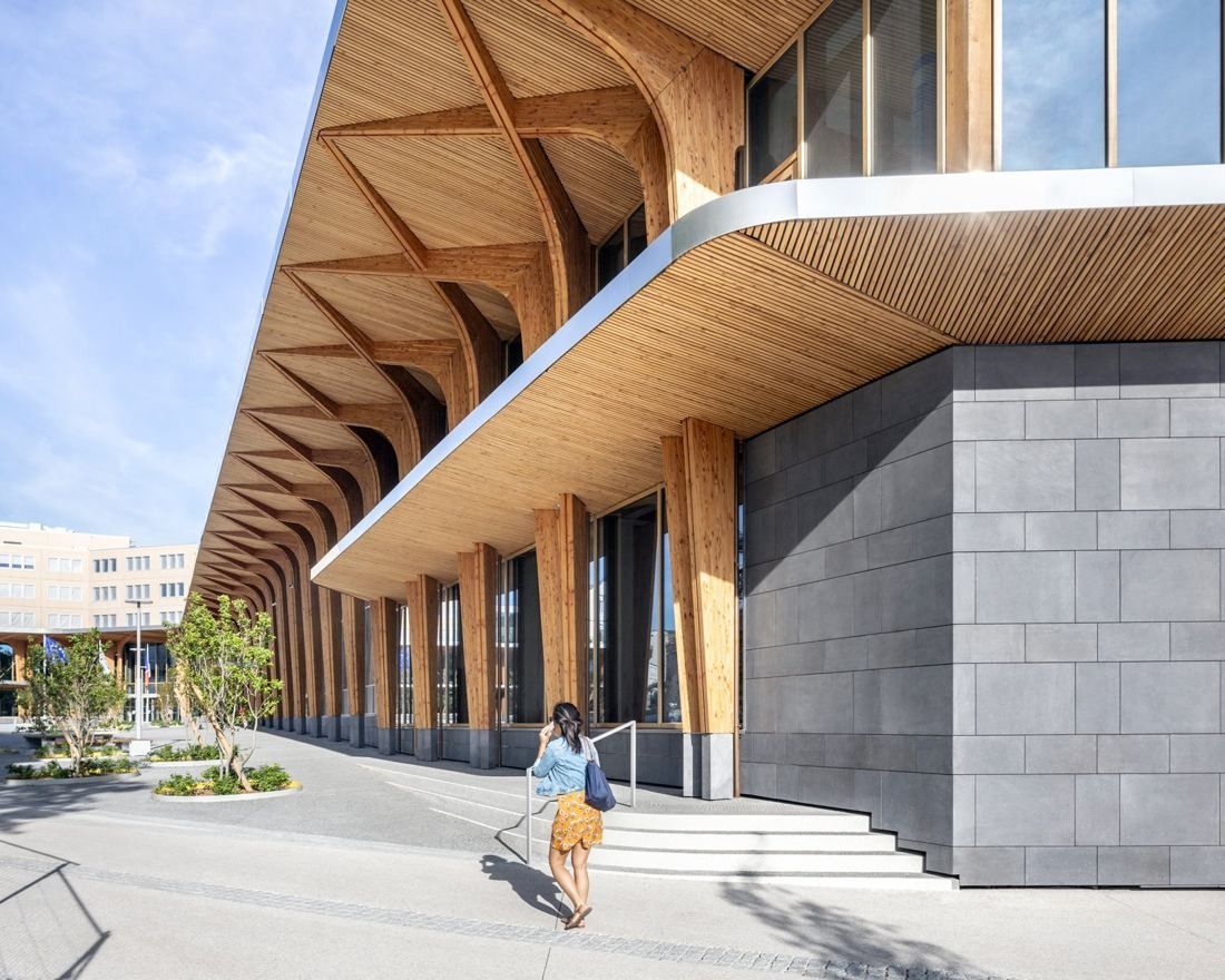 Michelin: Timber canopy above a dark stone-clad wall with steps, a person walking from behind