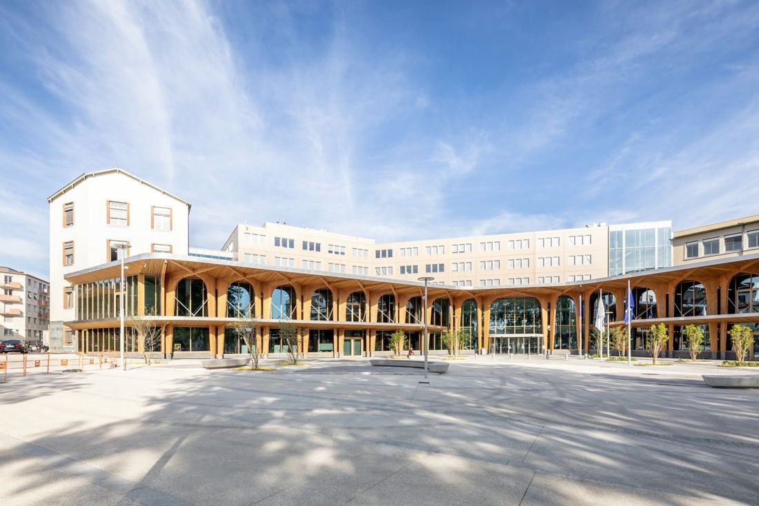 Michelin: Wide paved square in front of a long low timber-arched building and older white headquarters blocks