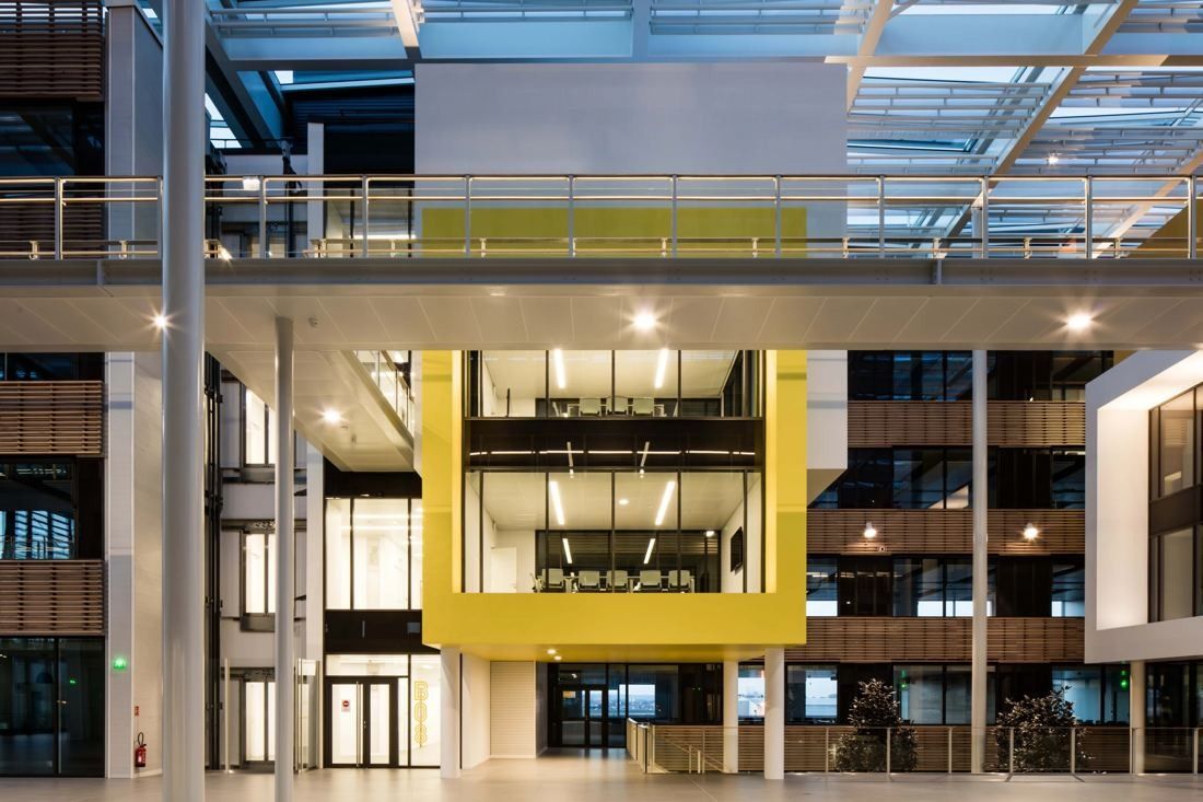 Michelin: Yellow-framed glazed volume between office floors under a glass roof