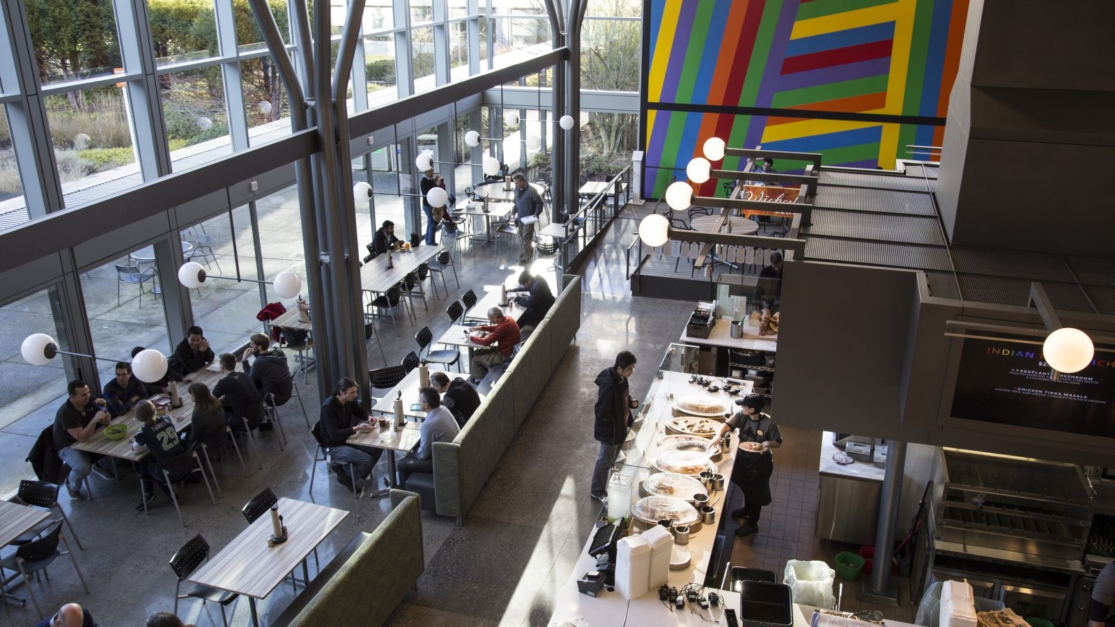Two-storey café with long tables and a colourful wall