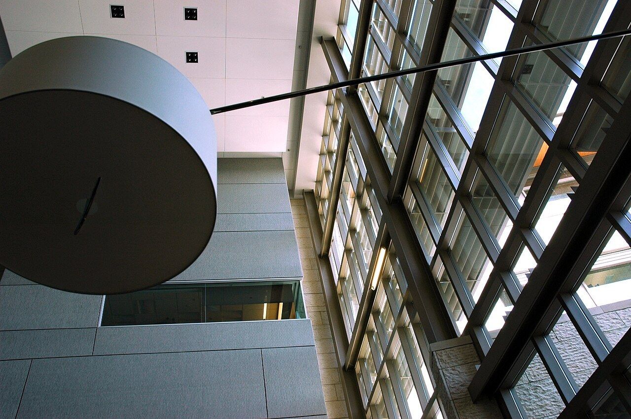 A large round lamp and tall glass walls inside Studio D