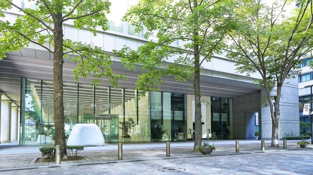 Mitsubishi Corporation: Glass entrance under a canopy, with trees in front